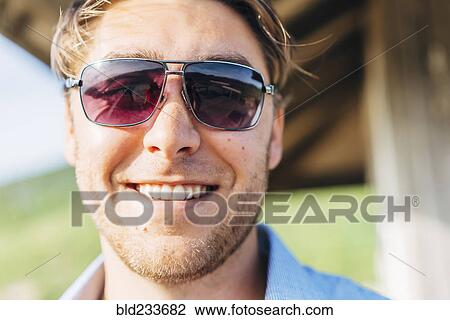 Stock Image - Smiling Caucasian man wearing sunglasses. Fotosearch