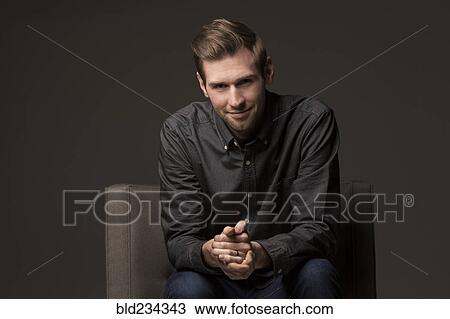 Smiling Caucasian man with hands clasped in armchair View Large Photo Image Stock Image - Smiling Caucasian man with hands clasped in armchair. Fotosearch