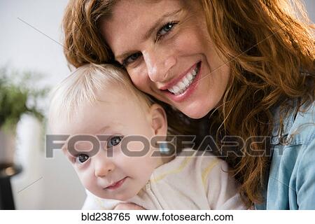 Stock Photography - Smiling Caucasian mother holding baby son. Fotosearch