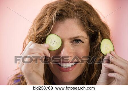Smiling Caucasian woman covering eye with cucumber slice View Large Photo Image Stock Photo - Smiling Caucasian woman covering eye with cucumber slice. Fotosearch