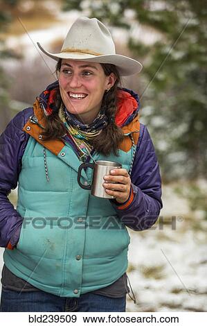 Stock Photo - Smiling Caucasian woman holding metal cup in winter. Fotosearch