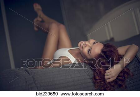 Smiling Caucasian woman laying on bed View Large Photo Image Stock Image - Smiling Caucasian woman laying on bed. Fotosearch