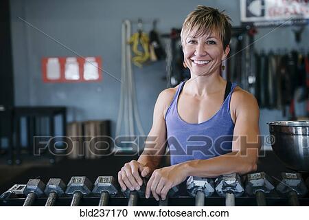 Smiling Caucasian woman leaning on rack in gymnasium View Large Photo Image Stock Image - Smiling Caucasian woman leaning on rack in gymnasium. Fotosearch