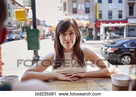 Stock Image - Smiling Caucasian woman leaning on counter in city. Fotosearch