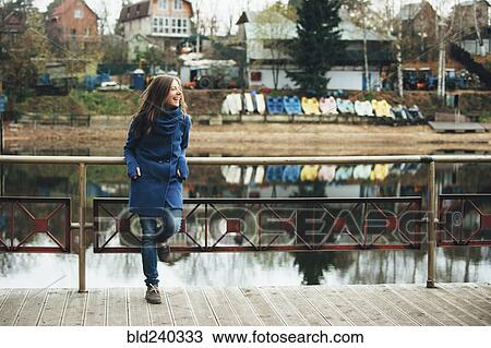 Smiling Caucasian woman leaning on bridge railing near river View Large Photo Image Stock Image - Smiling Caucasian woman leaning on bridge railing near river. Fotosearch