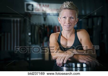 Stock Photo - Smiling Caucasian woman posing in gymnasium. Fotosearch