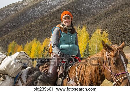 Stock Image - Smiling Caucasian woman riding horse in winter. Fotosearch
