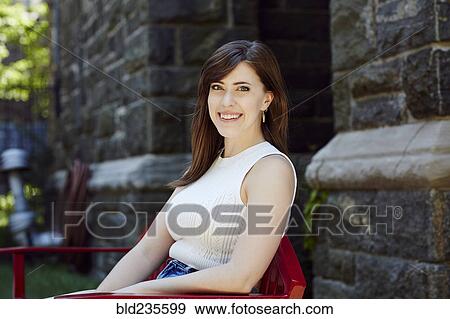 Smiling Caucasian woman sitting on chair outdoors View Large Photo Image Stock Photo - Smiling Caucasian woman sitting on chair outdoors. Fotosearch