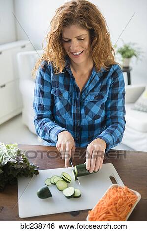 Smiling Caucasian woman slicing cucumbers View Large Photo Image Stock Photograph - Smiling Caucasian woman slicing cucumbers. Fotosearch