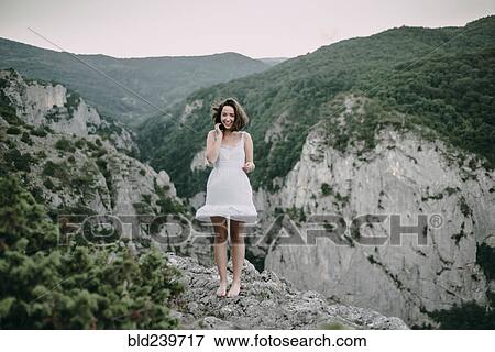 Stock Photo - Smiling Caucasian woman standing on mountain. Fotosearch