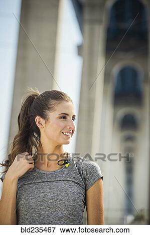 Stock Photo - Smiling Caucasian woman standing under overpass. Fotosearch