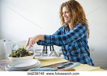 Stock Photo - Smiling Caucasian woman tossing salad. Fotosearch