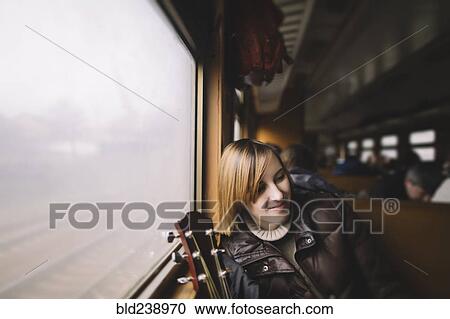 Smiling Caucasian woman with guitar sitting near window on train View Large Photo Image Stock Image - Smiling Caucasian woman with guitar sitting near window on train. Fotosearch