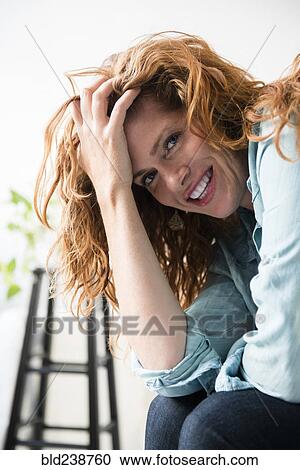 Stock Image - Smiling Caucasian woman with hand in hair. Fotosearch
