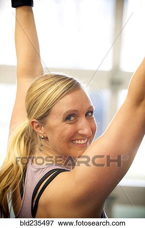 Stock Photo - Smiling Caucasian woman working out in gymnasium. Fotosearch