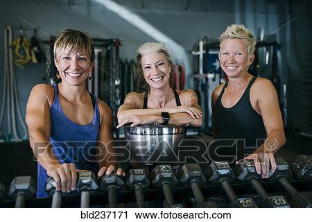Smiling Caucasian women leaning on rack in gymnasium View Large Photo Image Stock Image - Smiling Caucasian women leaning on rack in gymnasium. Fotosearch