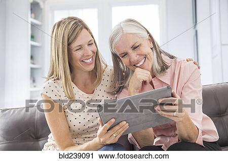 Stock Image - Smiling Caucasian women using digital tablet. Fotosearch