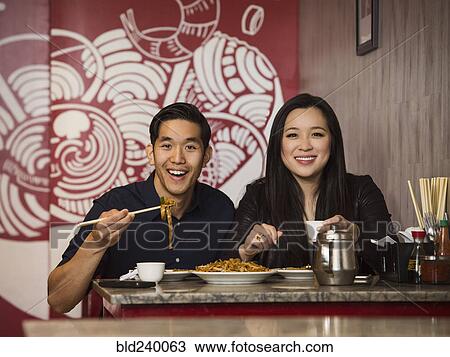 Stock Image - Smiling Chinese couple posing in restaurant. Fotosearch