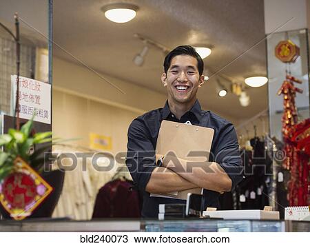 Smiling Chinese man posing with clipboard in store View Large Photo Image Stock Image - Smiling Chinese man posing with clipboard in store. Fotosearch