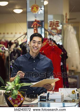 Smiling Chinese man writing on clipboard in store View Large Photo Image Stock Image - Smiling Chinese man writing on clipboard in store. Fotosearch