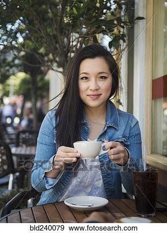 Smiling Chinese woman drinking coffee at outdoor cafe View Large Photo Image Stock Photo - Smiling Chinese woman drinking coffee at outdoor cafe. Fotosearch