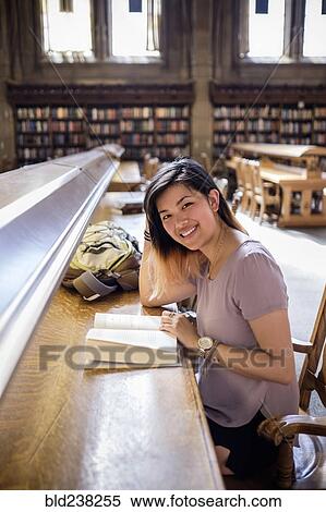 Smiling Chinese woman sitting in library reading book View Large Photo Image Stock Photography - Smiling Chinese woman sitting in library reading book. Fotosearch