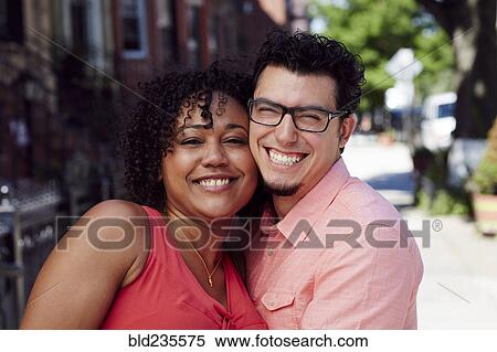 Stock Photography - Smiling couple cheek to cheek in city. Fotosearch