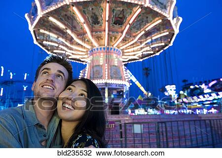 Stock Image - Smiling couple cheek to cheek in amusement park. Fotosearch