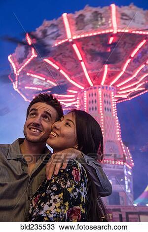Stock Image - Smiling couple cheek to cheek in amusement park. Fotosearch