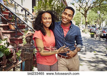 Stock Photography - Smiling couple posing on city sidewalk. Fotosearch