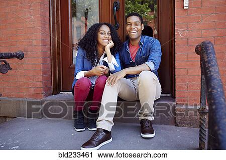 Stock Image - Smiling couple posing on front stoop. Fotosearch
