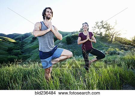Smiling couple practicing yoga on hill View Large Photo Image Picture - Smiling couple practicing yoga on hill. Fotosearch