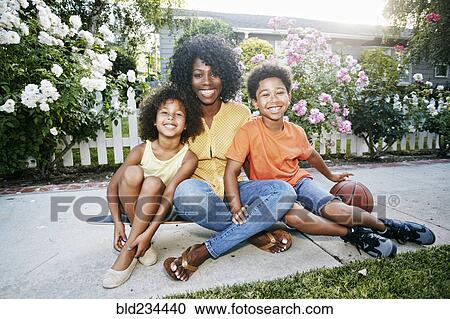 Stock Image - Smiling family sitting on skateboard. Fotosearch