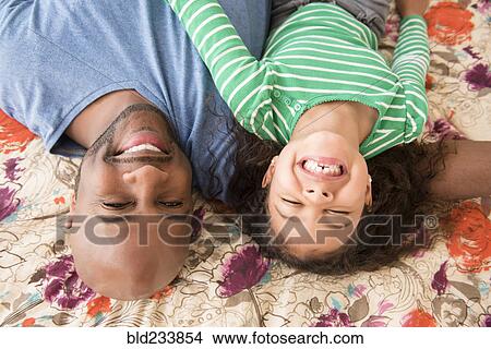 Picture - Smiling father and daughter laying on bed. Fotosearch