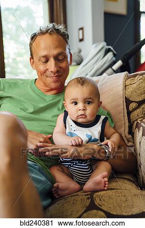 Stock Image - Smiling father holding baby son. Fotosearch