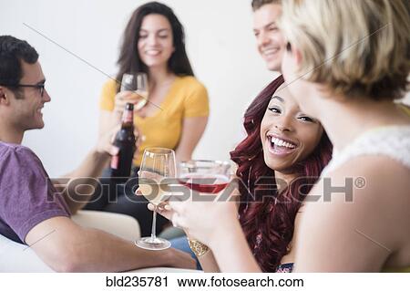 Stock Image - Smiling friends drinking at party. Fotosearch