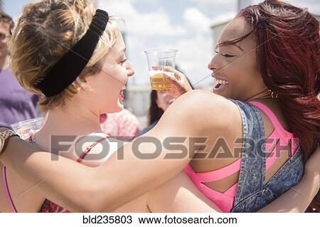 Stock Image - Smiling friends hugging outdoors. Fotosearch