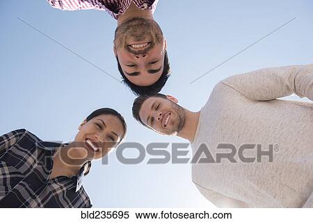 Stock Photography - Smiling friends losing under blue sky. Fotosearch