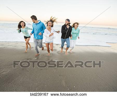 Smiling friends running on beach View Large Photo Image Stock Photo - Smiling friends running on beach. Fotosearch