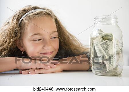 Smiling girl saving money in jar View Large Photo Image Stock Photograph - Smiling girl saving money in jar. Fotosearch