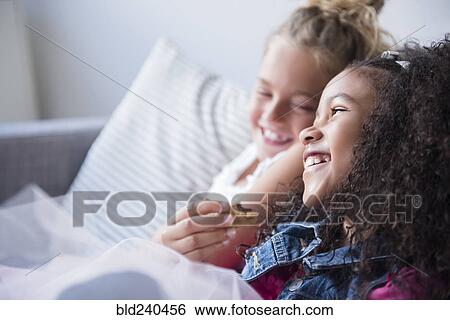 Smiling girls eating cookie on sofa View Large Photo Image Stock Photograph - Smiling girls eating cookie on sofa. Fotosearch