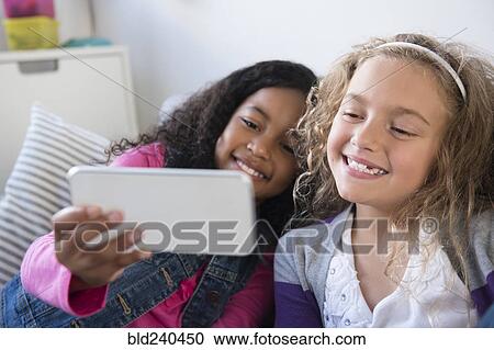 Smiling girls posing for cell phone selfie View Large Photo Image Stock Image - Smiling girls posing for cell phone selfie. Fotosearch