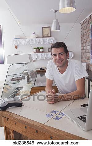 Stock Photograph - Smiling Hispanic baker leaning on counter. Fotosearch