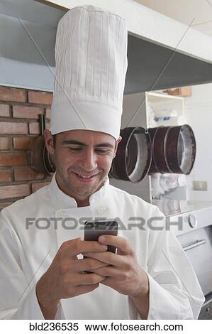 Smiling Hispanic chef texting on cell phone View Large Photo Image Stock Photography - Smiling Hispanic chef texting on cell phone. Fotosearch