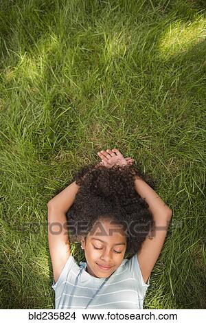 Picture - Smiling Hispanic girl laying in grass. Fotosearch