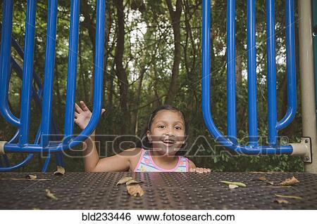 Stock Photograph - Smiling Hispanic girl reaching on playground. Fotosearch