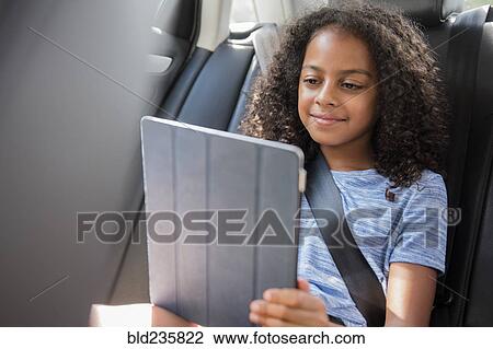 Smiling Hispanic girl using digital tablet in car View Large Photo Image Stock Image - Smiling Hispanic girl using digital tablet in car. Fotosearch