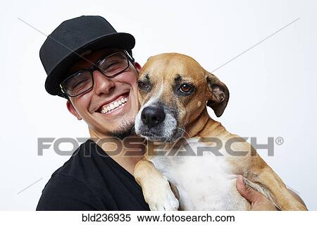 Stock Photography - Smiling Hispanic man hugging dog. Fotosearch