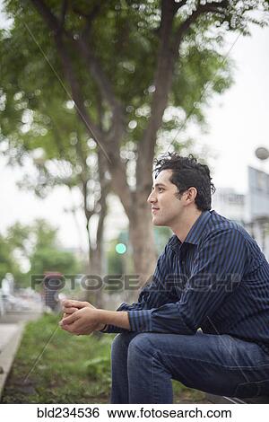 Smiling Hispanic man sitting on bench View Large Photo Image Stock Photograph - Smiling Hispanic man sitting on bench. Fotosearch