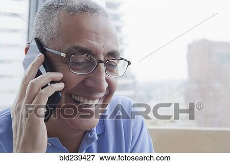 Stock Photo - Smiling Hispanic man talking on cell phone. Fotosearch